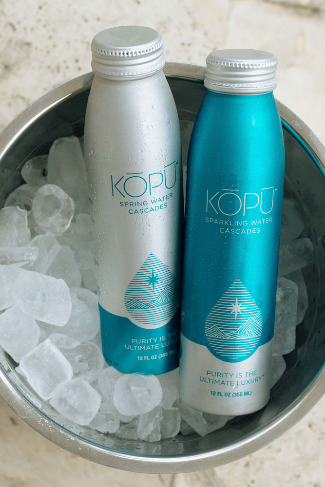KOPU sparkling and spring water aluminum cans in bucket of ice.